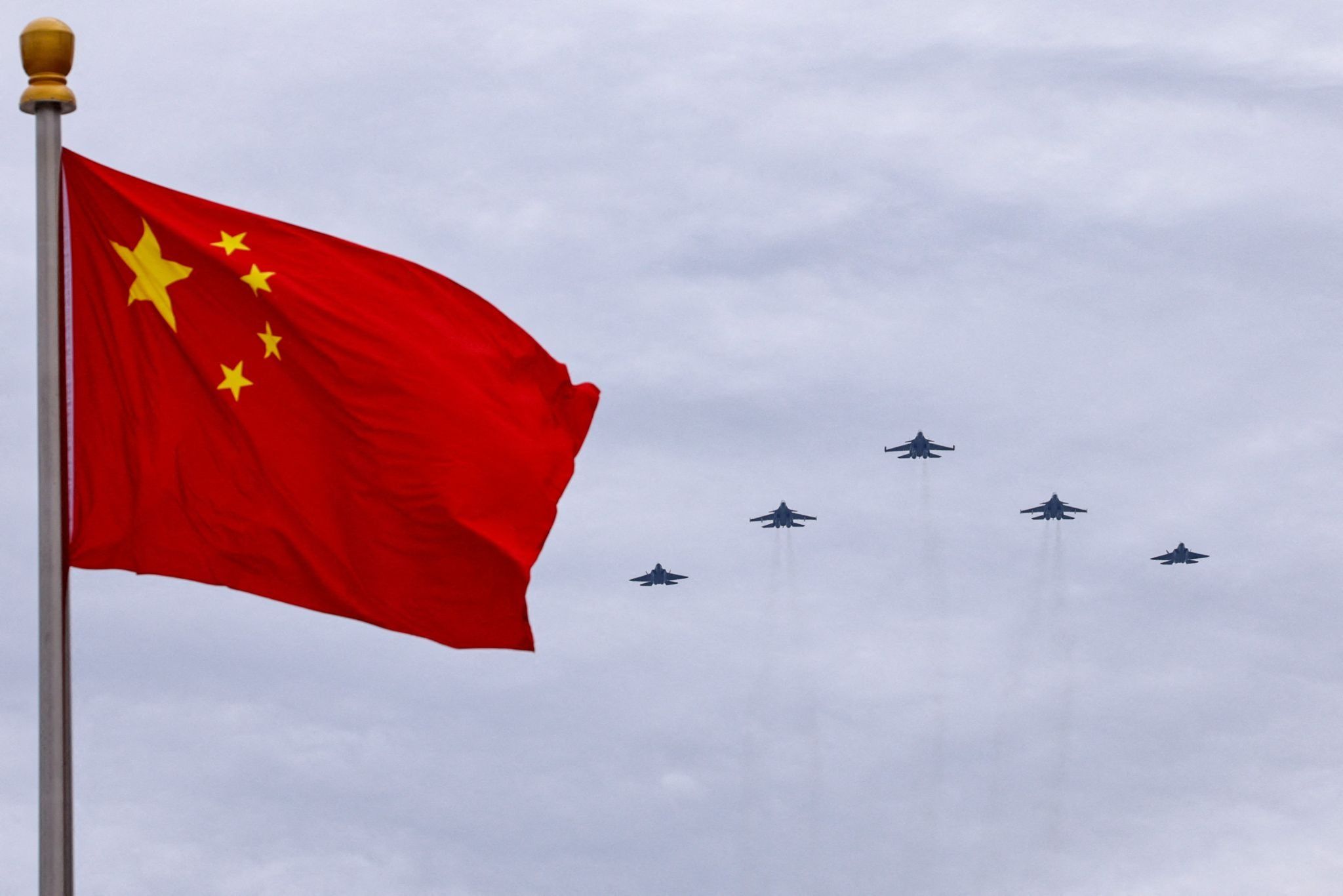 Chinese jets fly in formation with a flag in the foreground