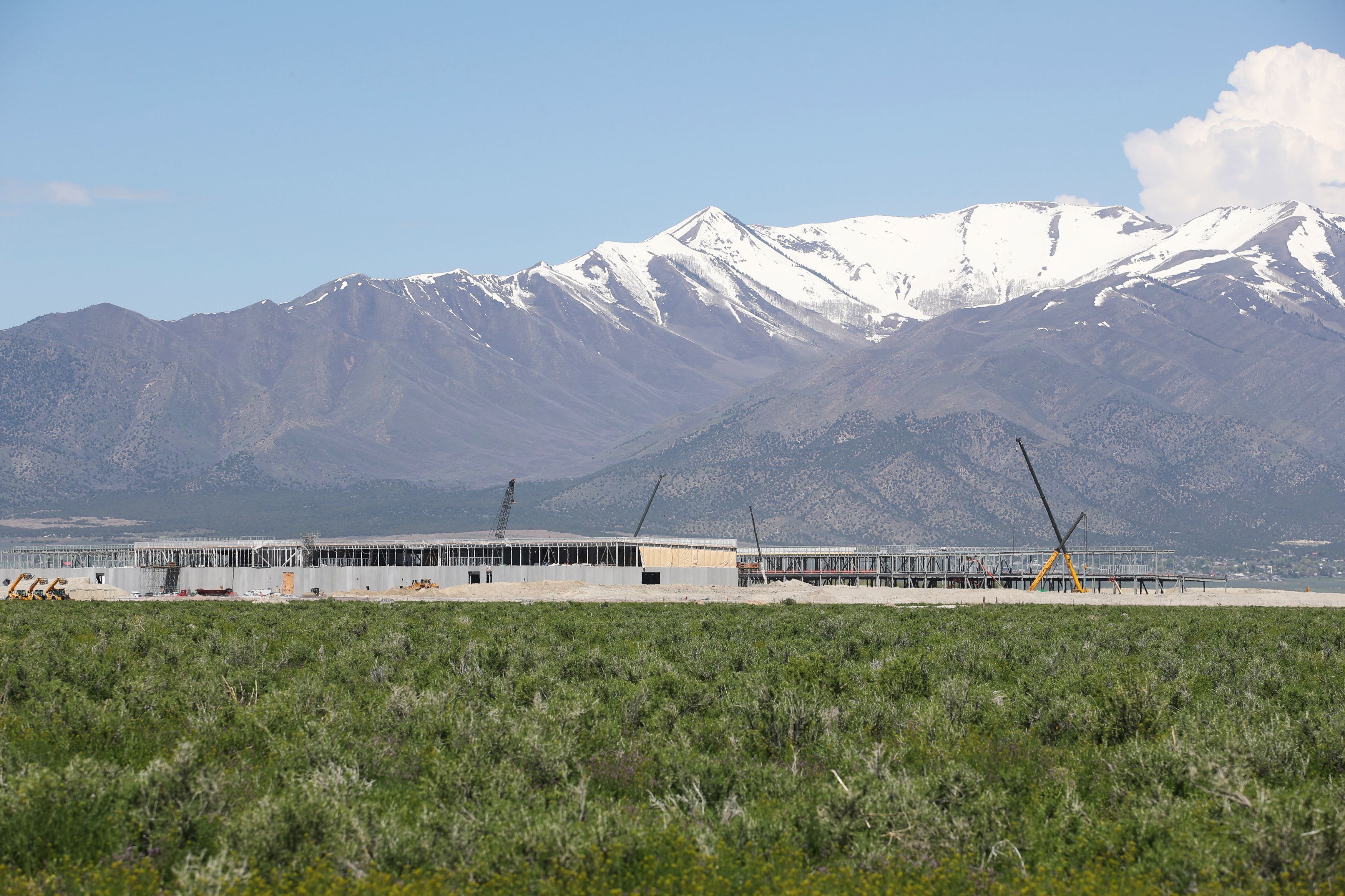 With snow-covered Flat Top Mountain in the background, construction workers build a new Facebook data center in Eagle Mountain, Utah.