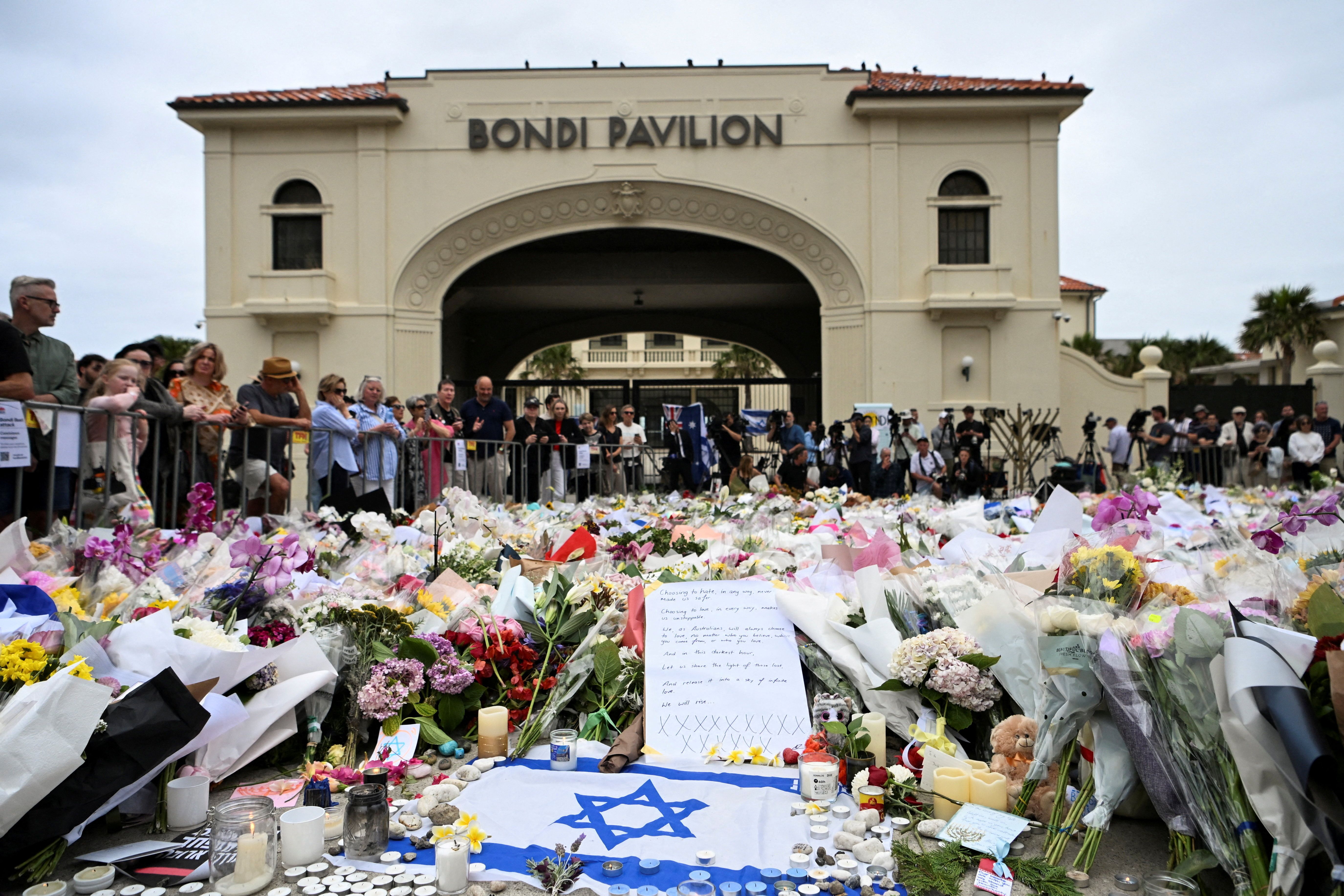 People stand near flowers laid as a tribute at Bondi Beach.