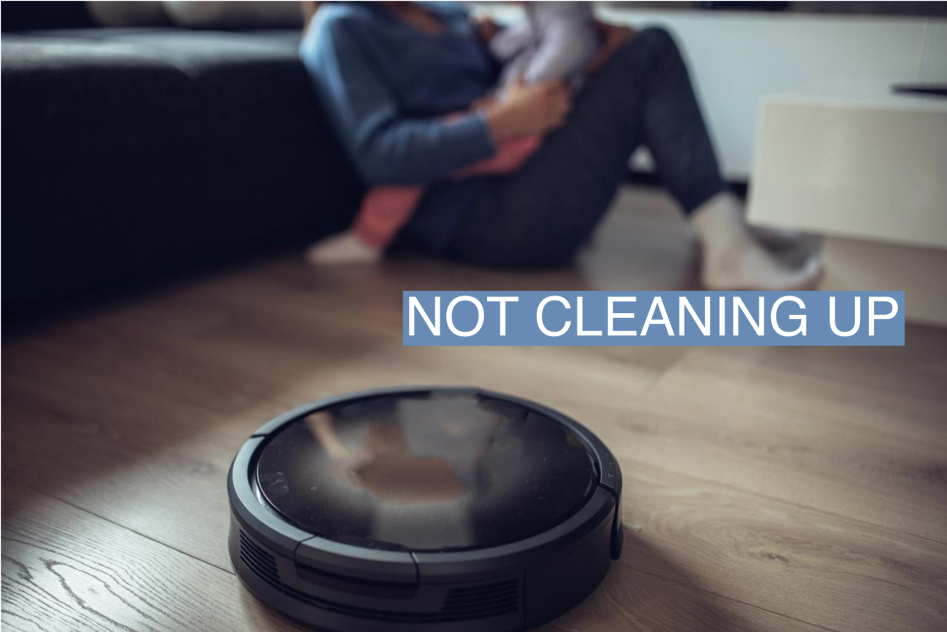 Robotic Vacuum Cleaner Cleaning Floor While Mother and Daughter Playing on the sofa