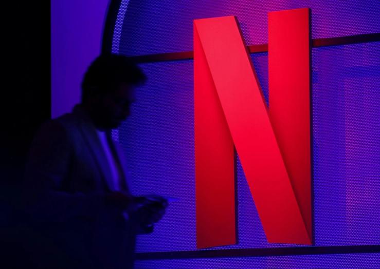 A man stands next to a logo of Netflix during an event in Mumbai.