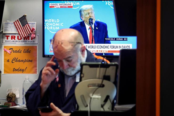 A trader works, as a screen displays U.S. President Donald Trump speaking at the World Economic Forum (WEF)