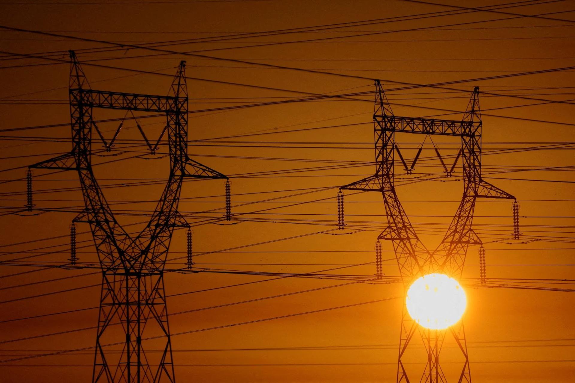 Electrical power pylons of high-tension electricity power lines are seen during sunset.