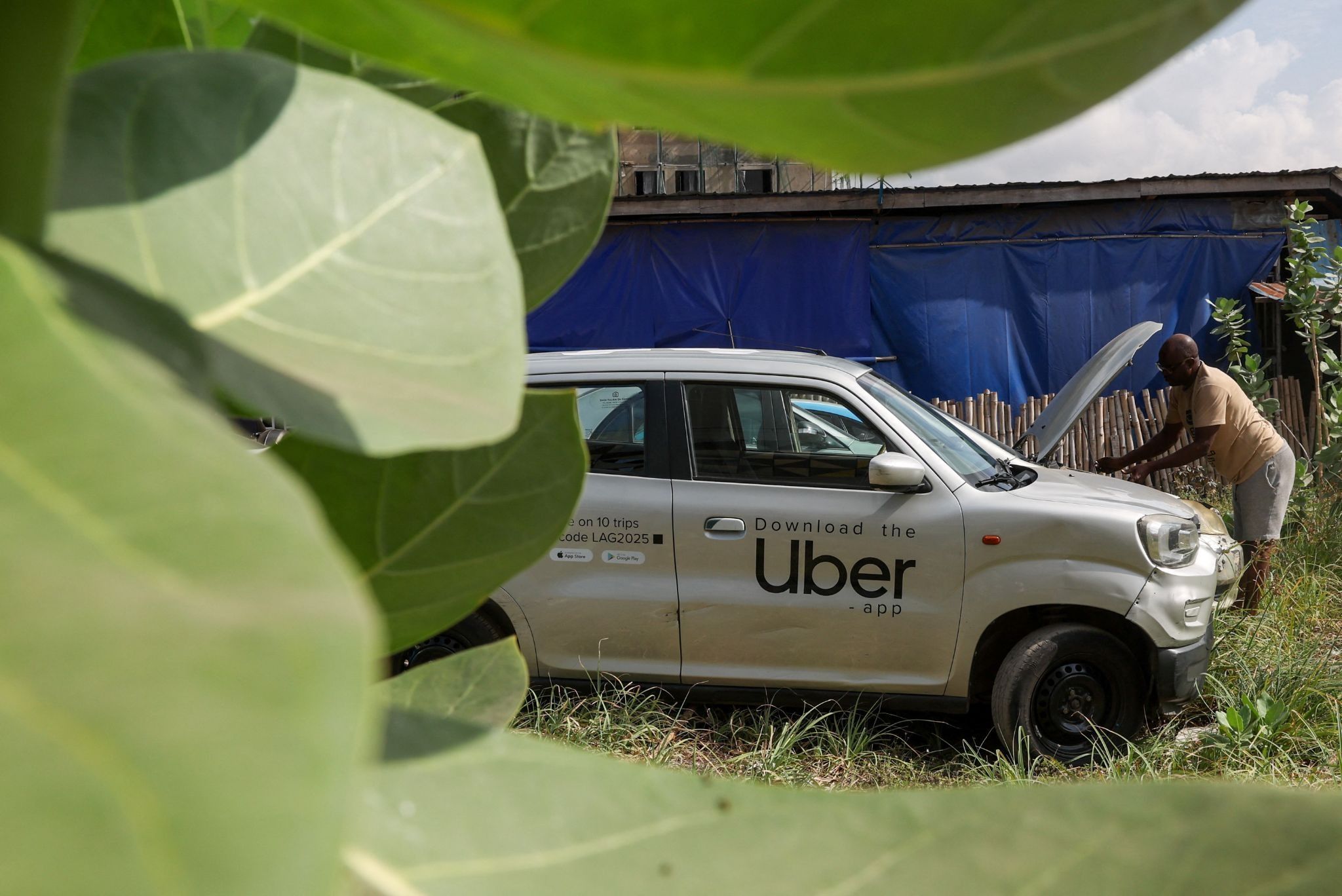 A Nigerian ride-hailing driver working with Uber fixes his car