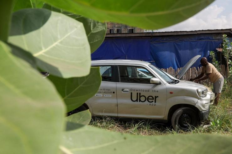 A Nigerian ride-hailing driver working with Uber fixes his car