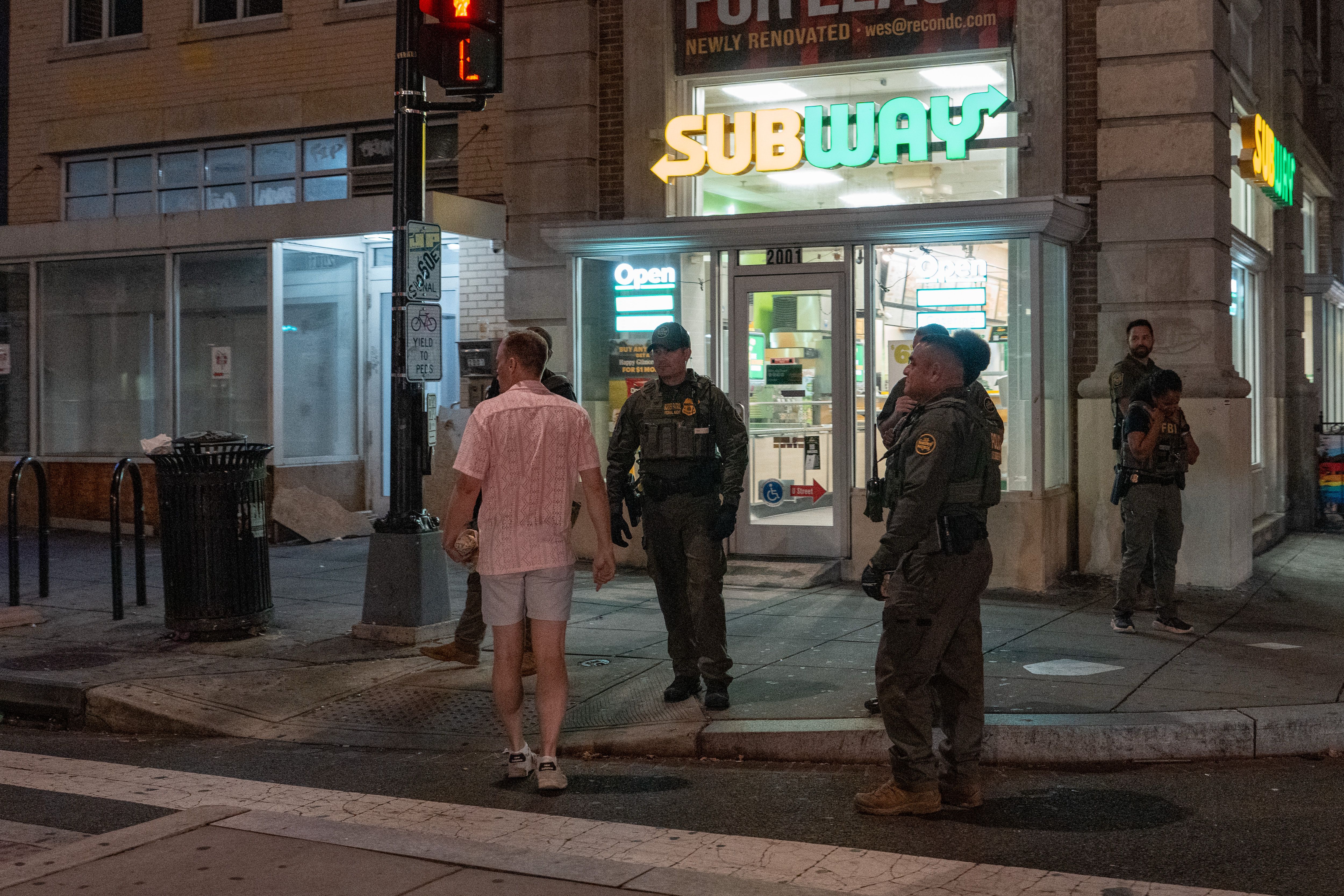 A man, who was later arrested. for assaulting law enforcement with a sandwich, interacts with Border Patrol and FBI agents along the U Street corridor on August 10, 2025, in Washington, DC. 