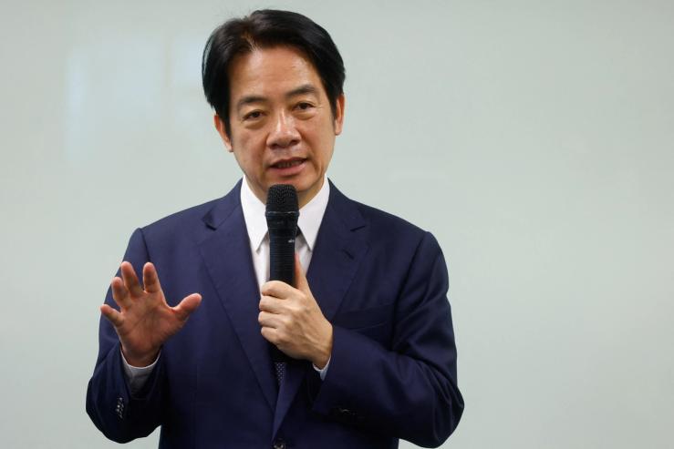 Taiwan’s President William Lai in a dark blue suit, holding a microphone