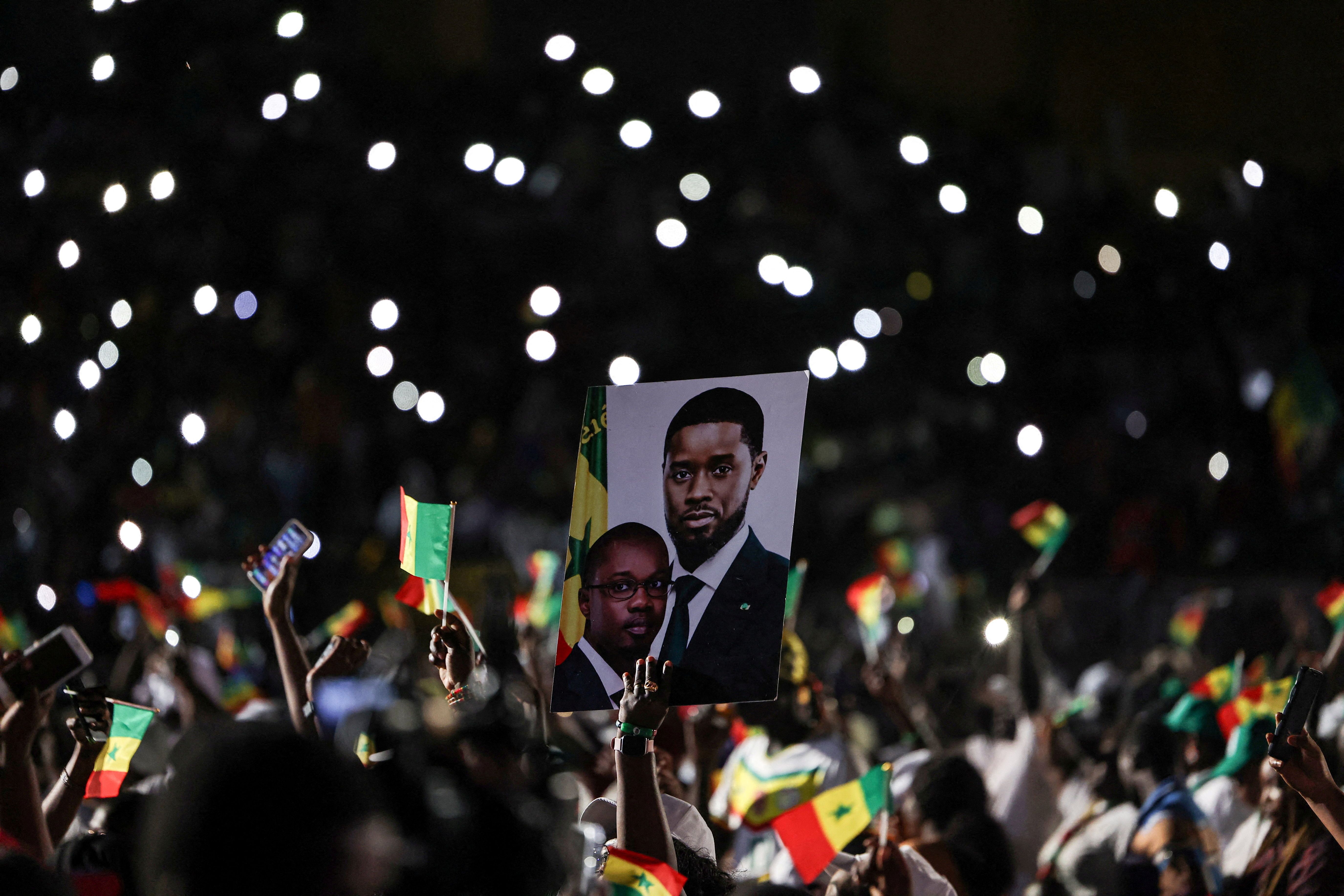A supporter holds a campaign poster depicting Senegal’s President Bassirou Diomaye Faye and Prime Minister Ousmane Sonko.
