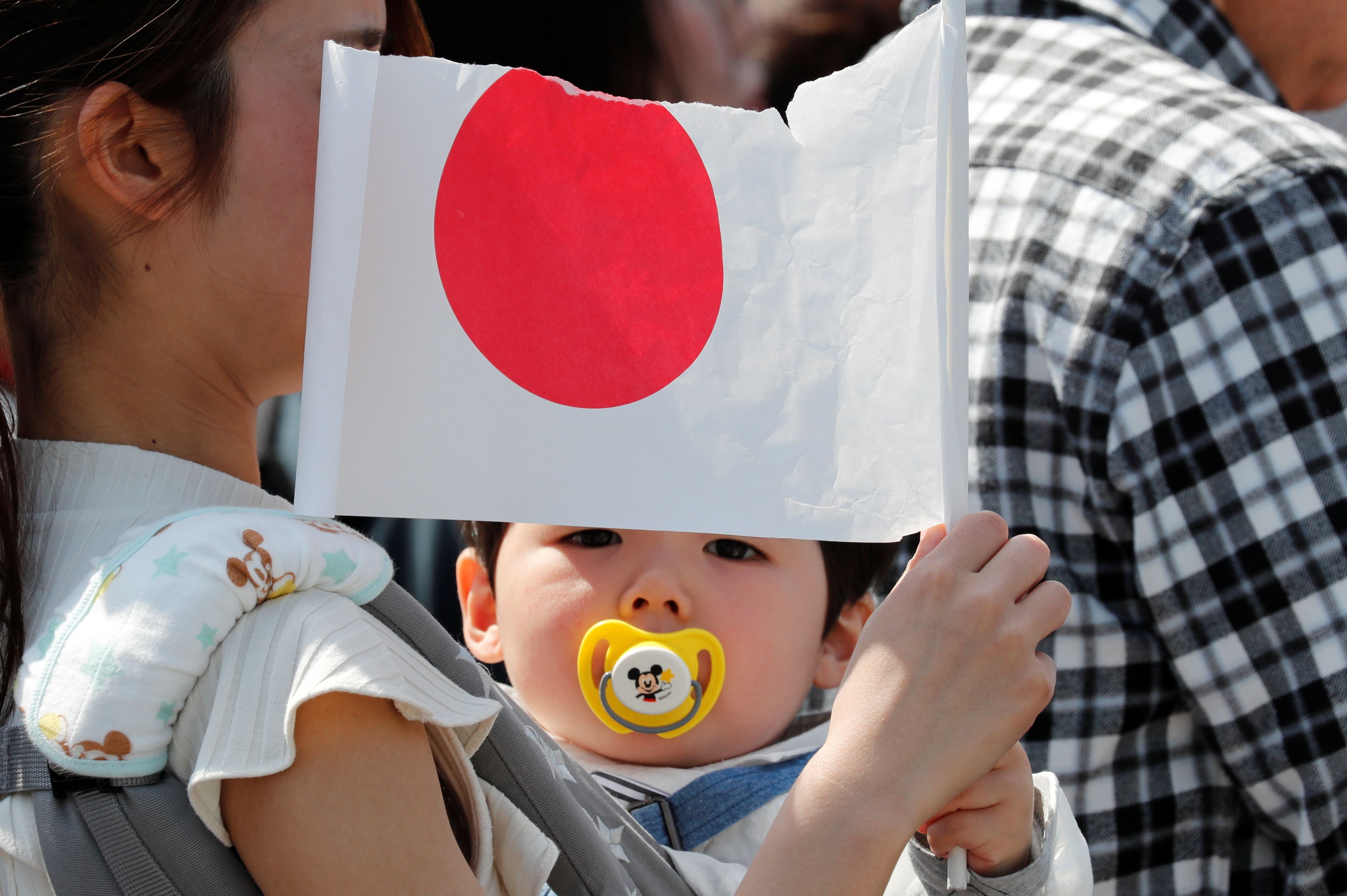 A baby holds a Japanese national flag.