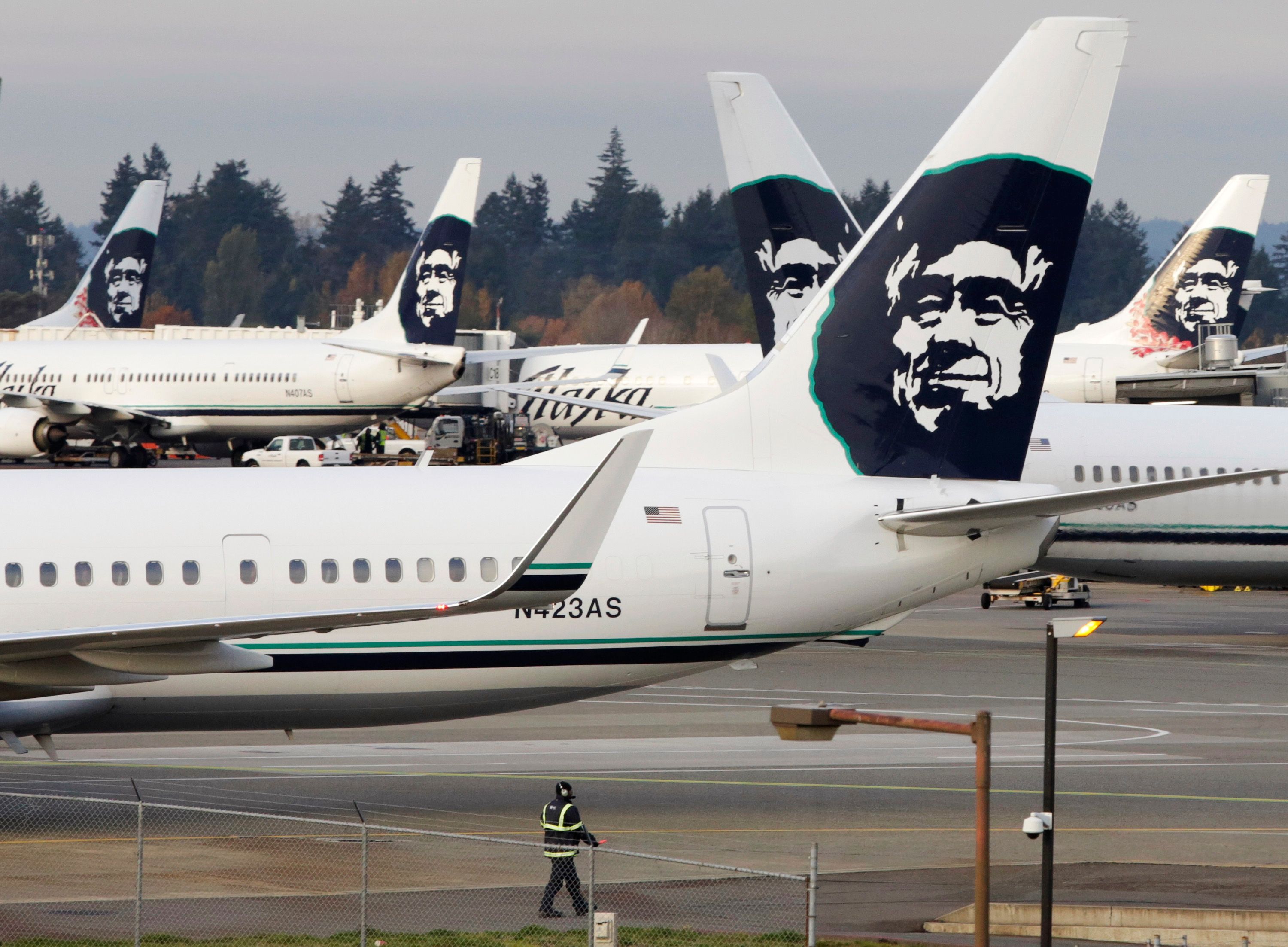 A ground crew member walks near Alaska Airlines planes parked at Seattle-Tacoma International Airport in SeaTac.