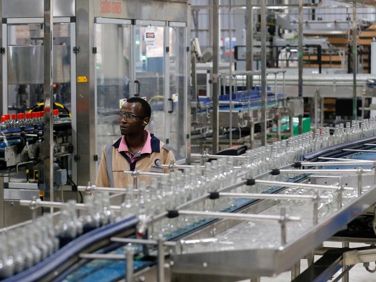 An employee walks near Kenya Cane spirit bottles at a factory in Nairobi, Kenya.