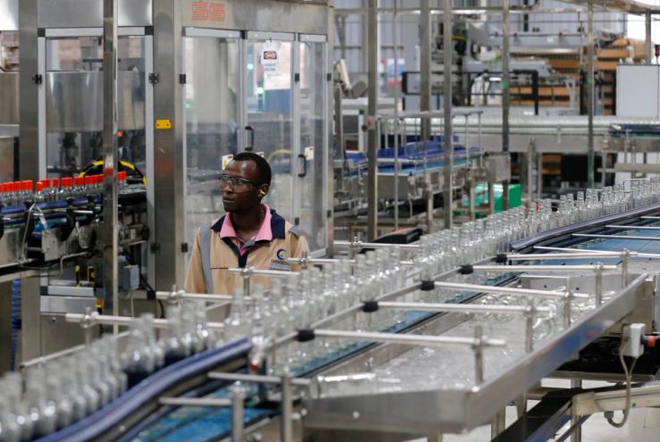 An employee walks near Kenya Cane spirit bottles at a factory in Nairobi, Kenya.