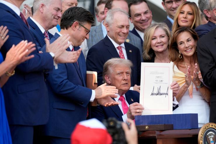 President Donald Trump holds up his signed signature bill of tax breaks and spending cuts, ahead of the Fourth of July celebrations, at the White House in Washington.