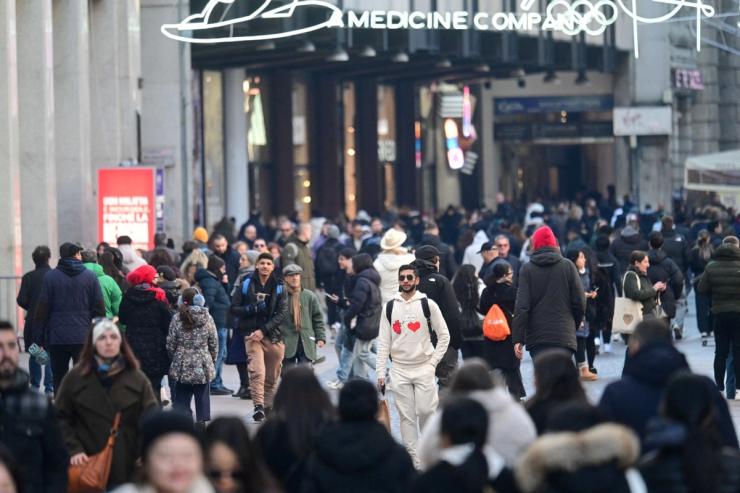 People walk through a crowded shopping street in central Milan.