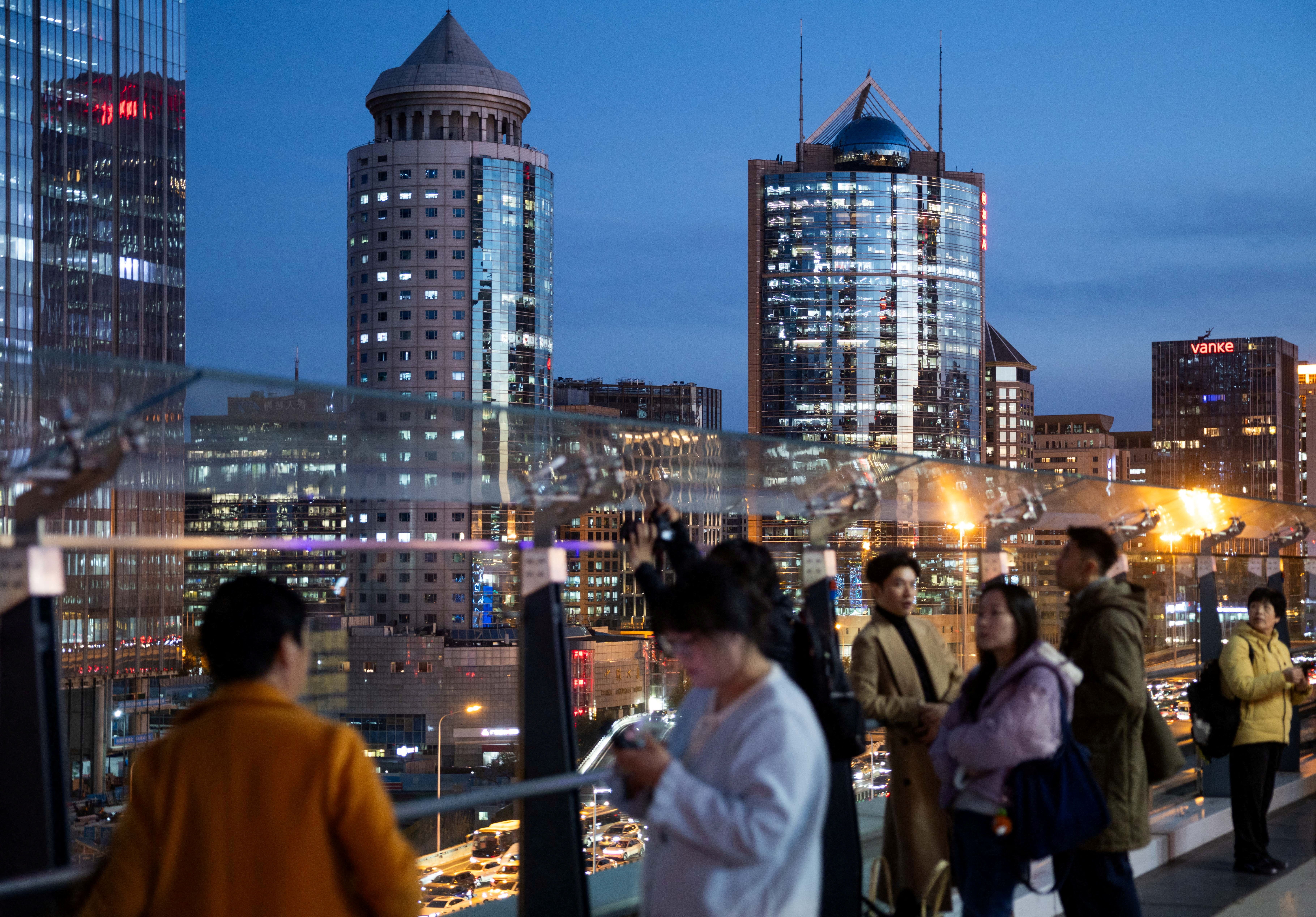 People stand at an observation deck with a view on office buildings of Beijing’s central business district.