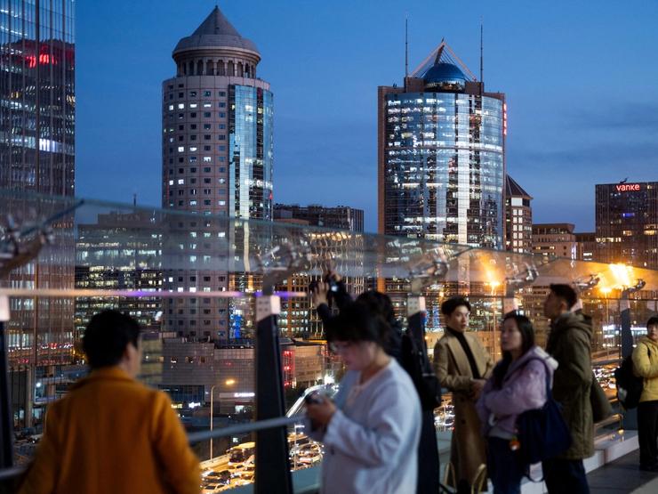 People stand at an observation deck with a view on office buildings of Beijing’s central business district.