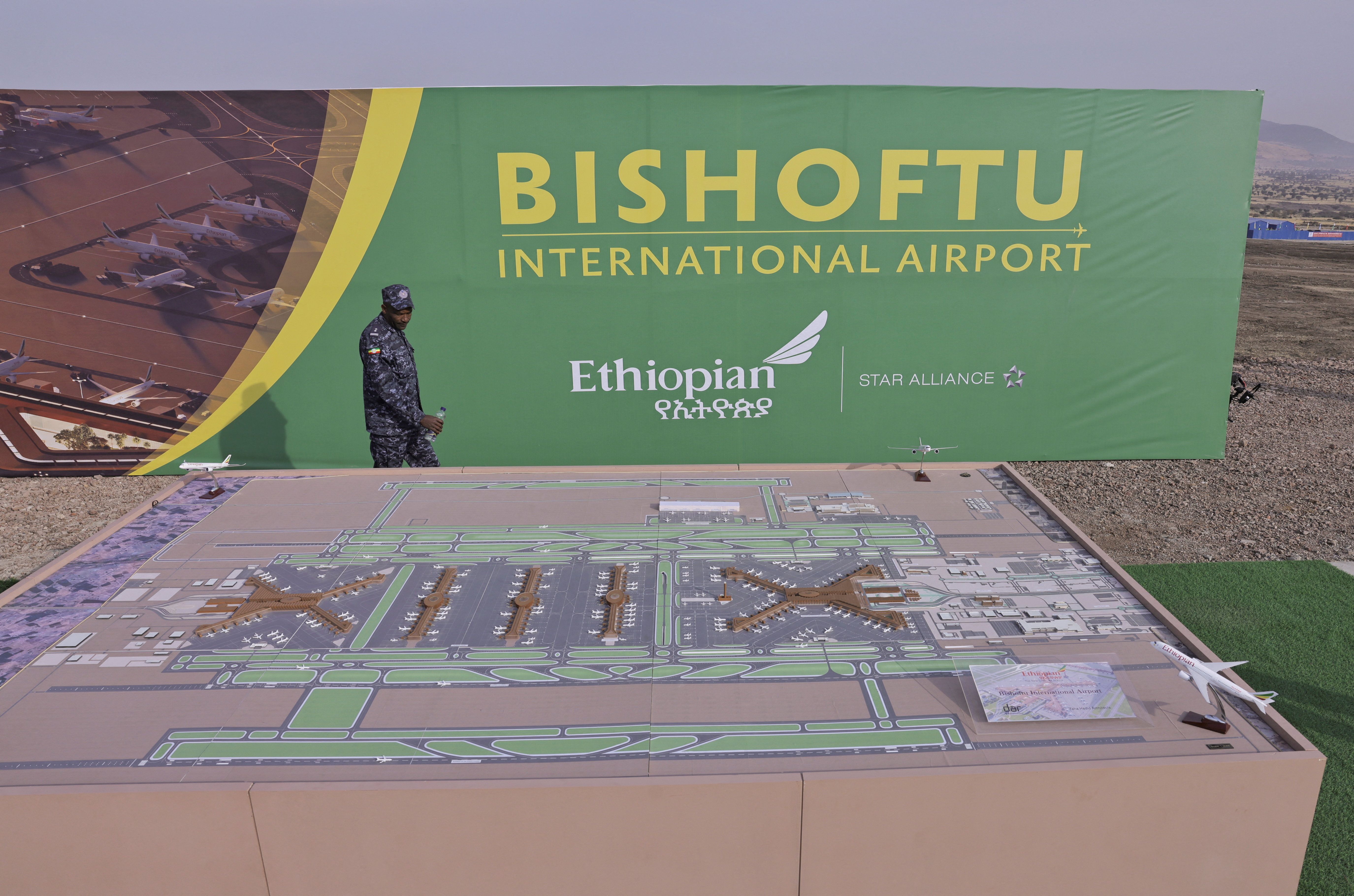 A member of the Ethiopian Federal Police walks past the Bishoftu International Airport design during its construction commencement in Abusera, Ethiopia.