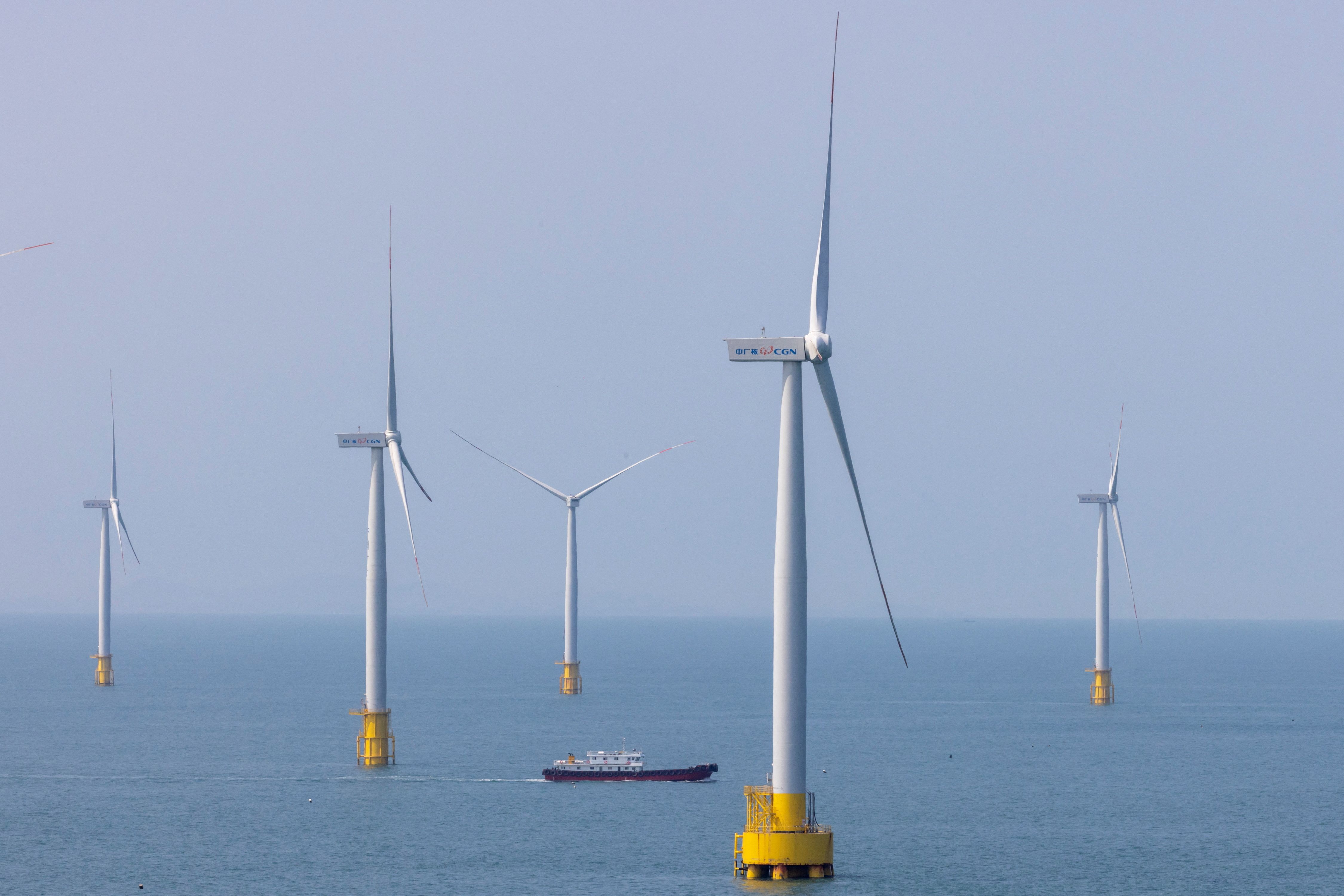 A ship sails between wind turbines in the Taiwan strait off the coast of Pingtan Island, China.
