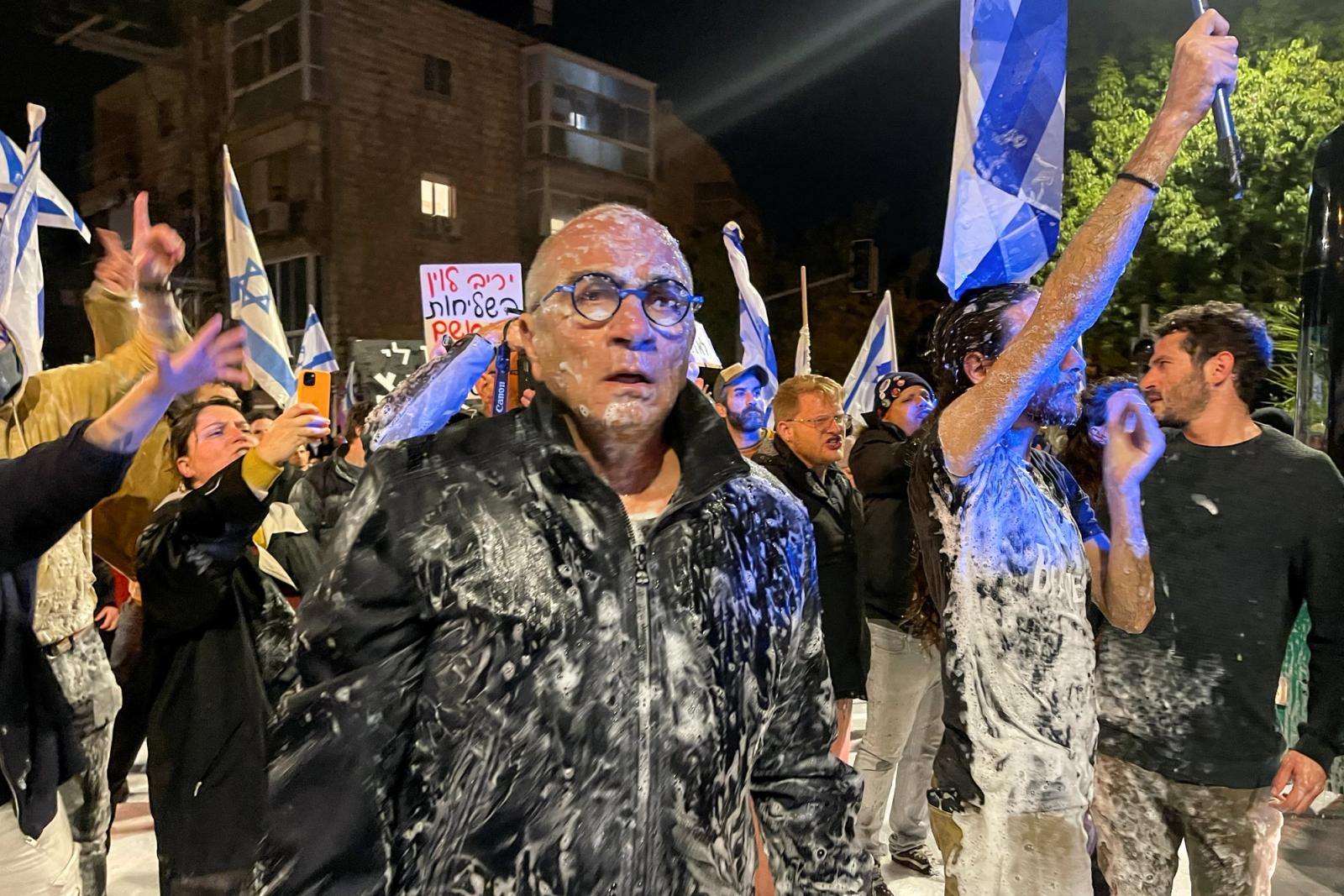 Protesters react after being sprayed by a water cannon as they demonstrate by the private home of Israeli Prime Minister Benjamin Netanyahu after he dismissed the defense minister and his nationalist coalition government presses on with its judicial overhaul, in Jerusalem, March 26, 2023. REUTERS/Ilan Rosenberg