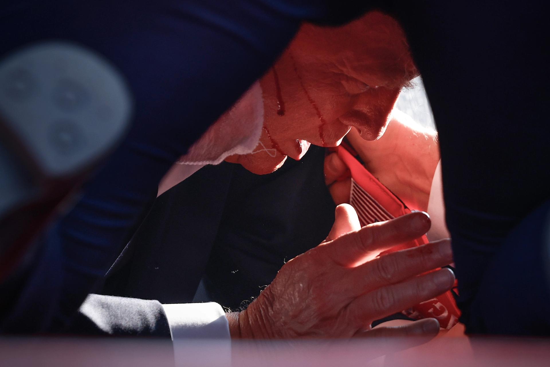 Trump is on the ground surrounded by Secret Service agents after apparent shots at his rally