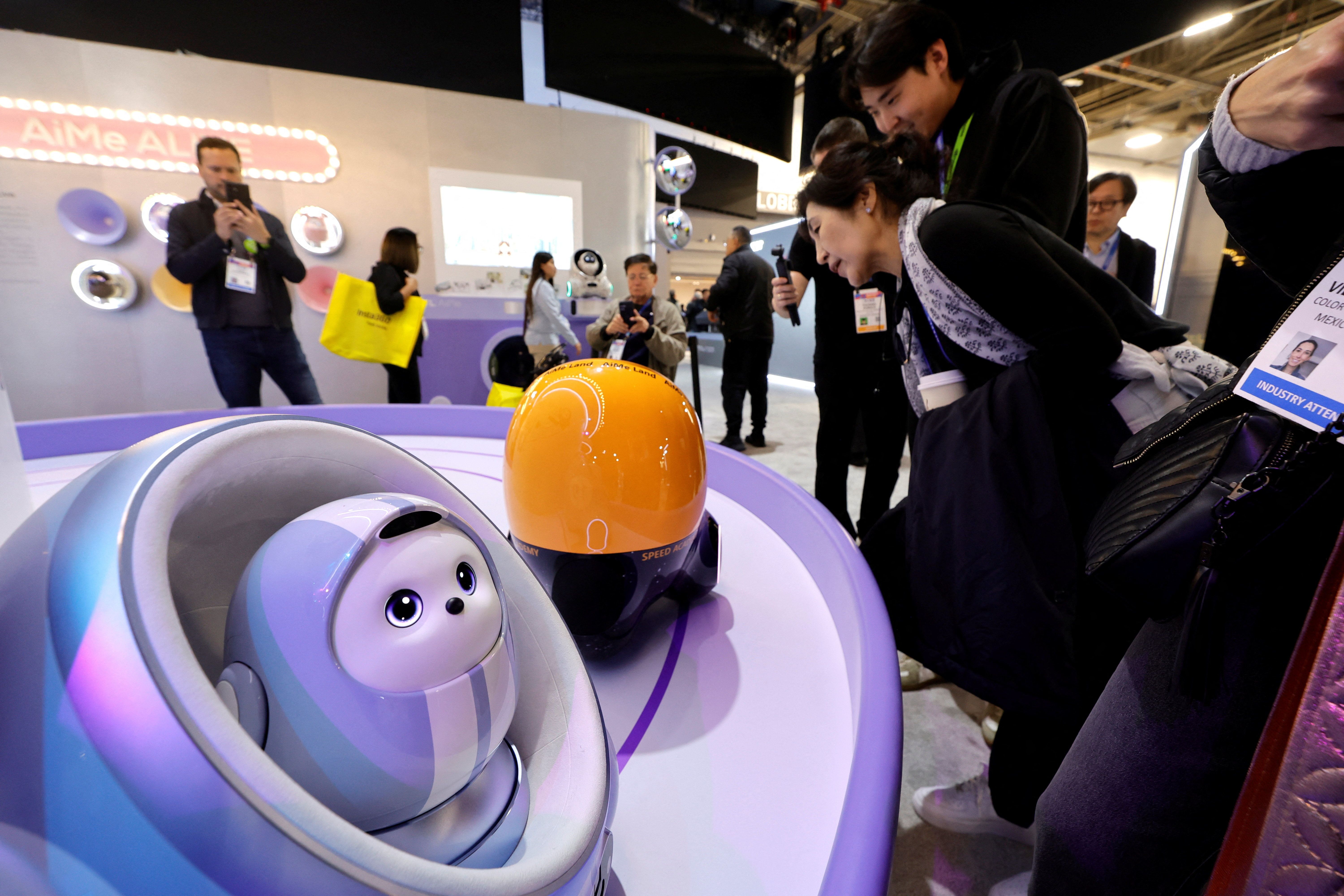 Attendees look at AiMe robots, AI companion robots for kids, at the TCL booth during CES 2026, an annual consumer electronics trade show, in Las Vegas, Nevada.