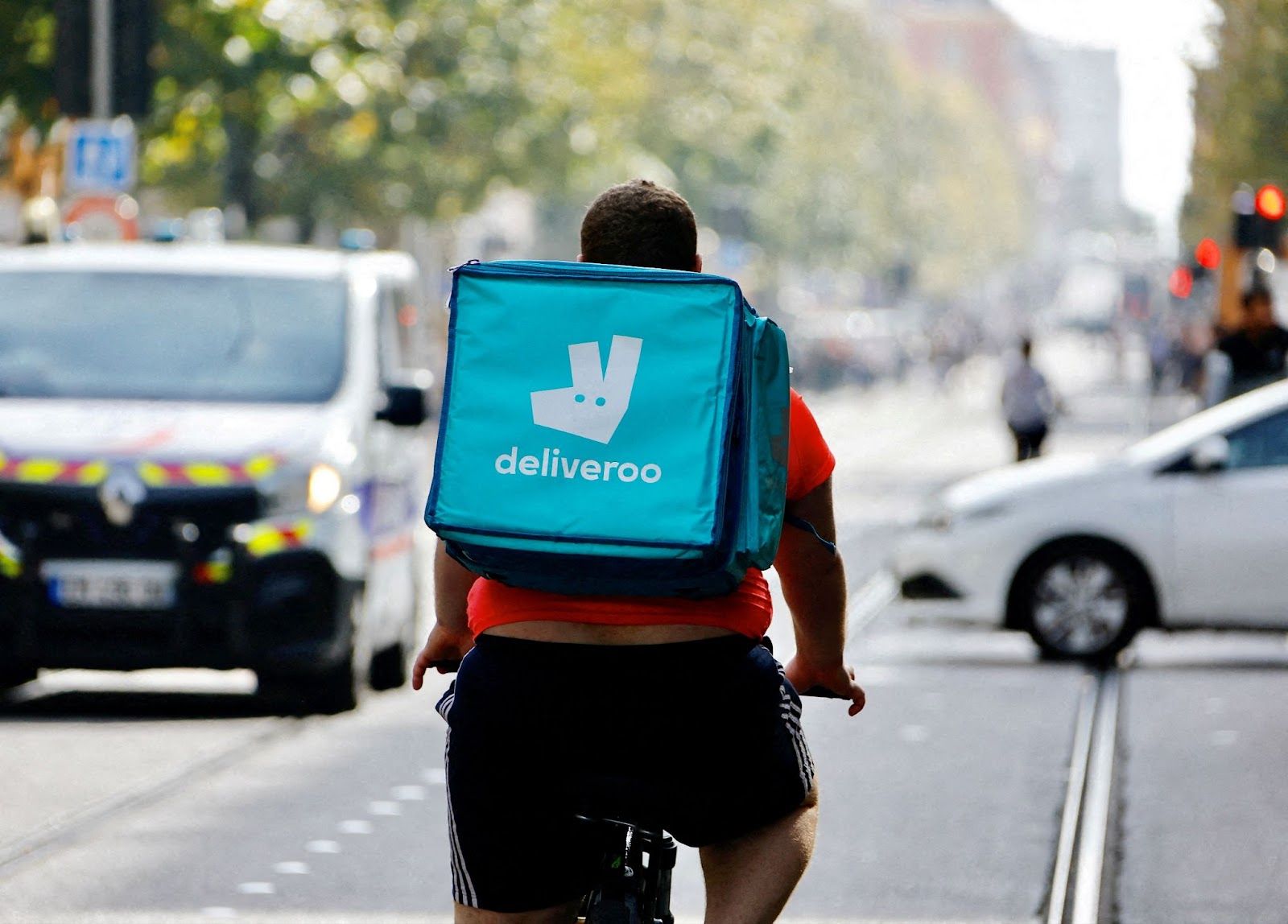 A delivery worker with a backpack of Deliveroo rides a bike. 