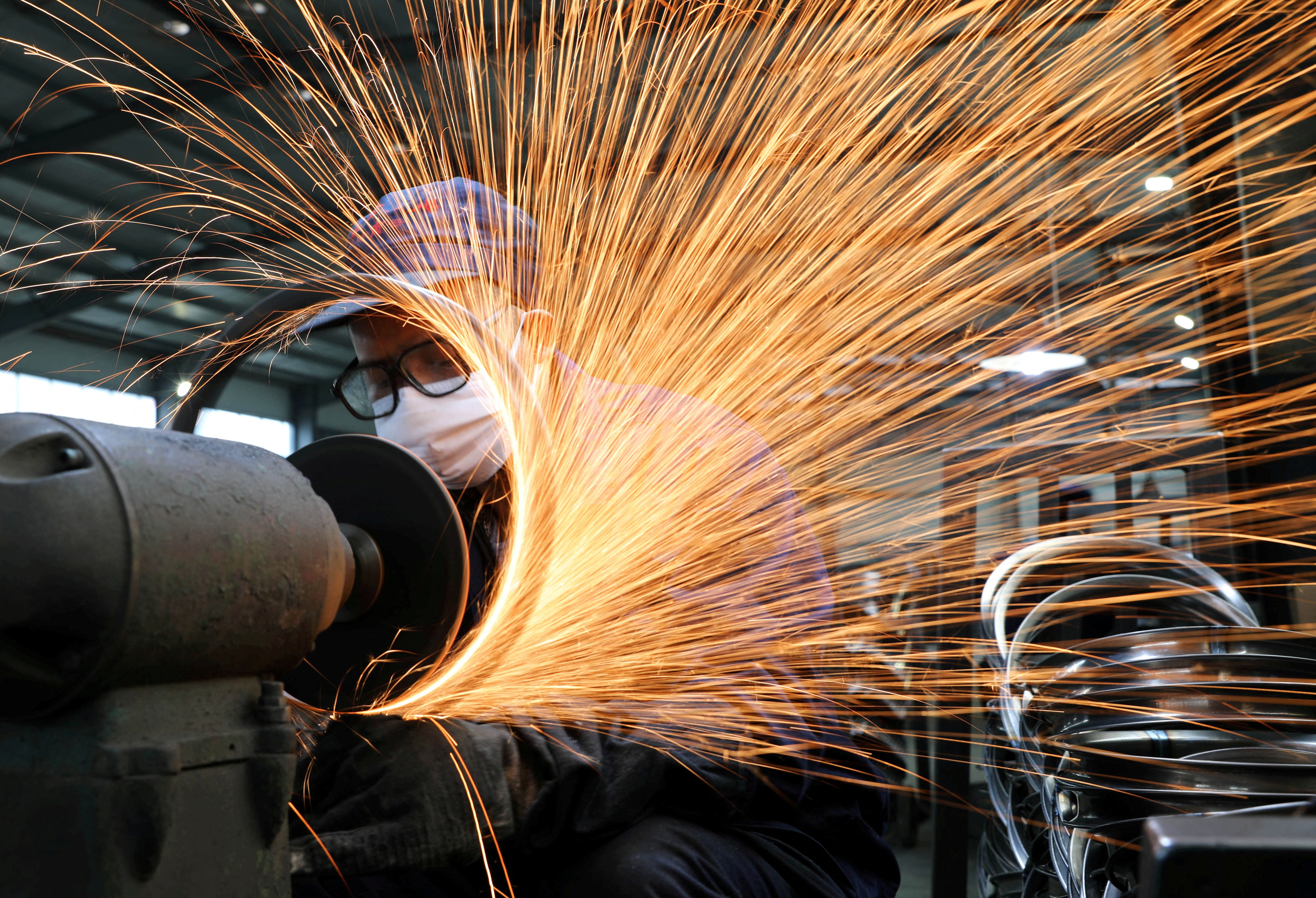 A worker wearing a face mask works on a production line manufacturing bicycle steel rim at a factory, as the country is hit by the novel coronavirus outbreak, in Hangzhou
