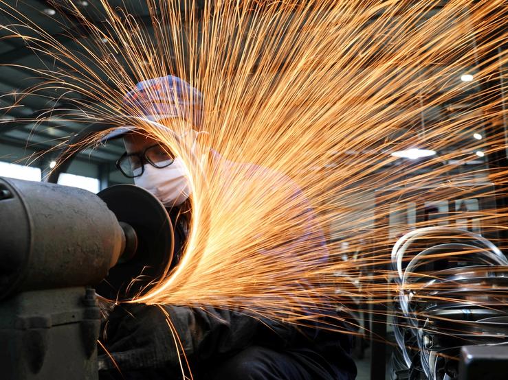 A worker wearing a face mask works on a production line manufacturing bicycle steel rim at a factory, as the country is hit by the novel coronavirus outbreak, in Hangzhou