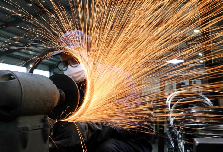 A worker wearing a face mask works on a production line manufacturing bicycle steel rim at a factory, as the country is hit by the novel coronavirus outbreak, in Hangzhou