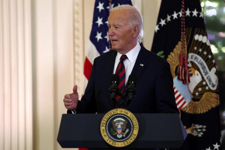Joe Biden, wearing a dark suit and striped tie, speaks at an event in December