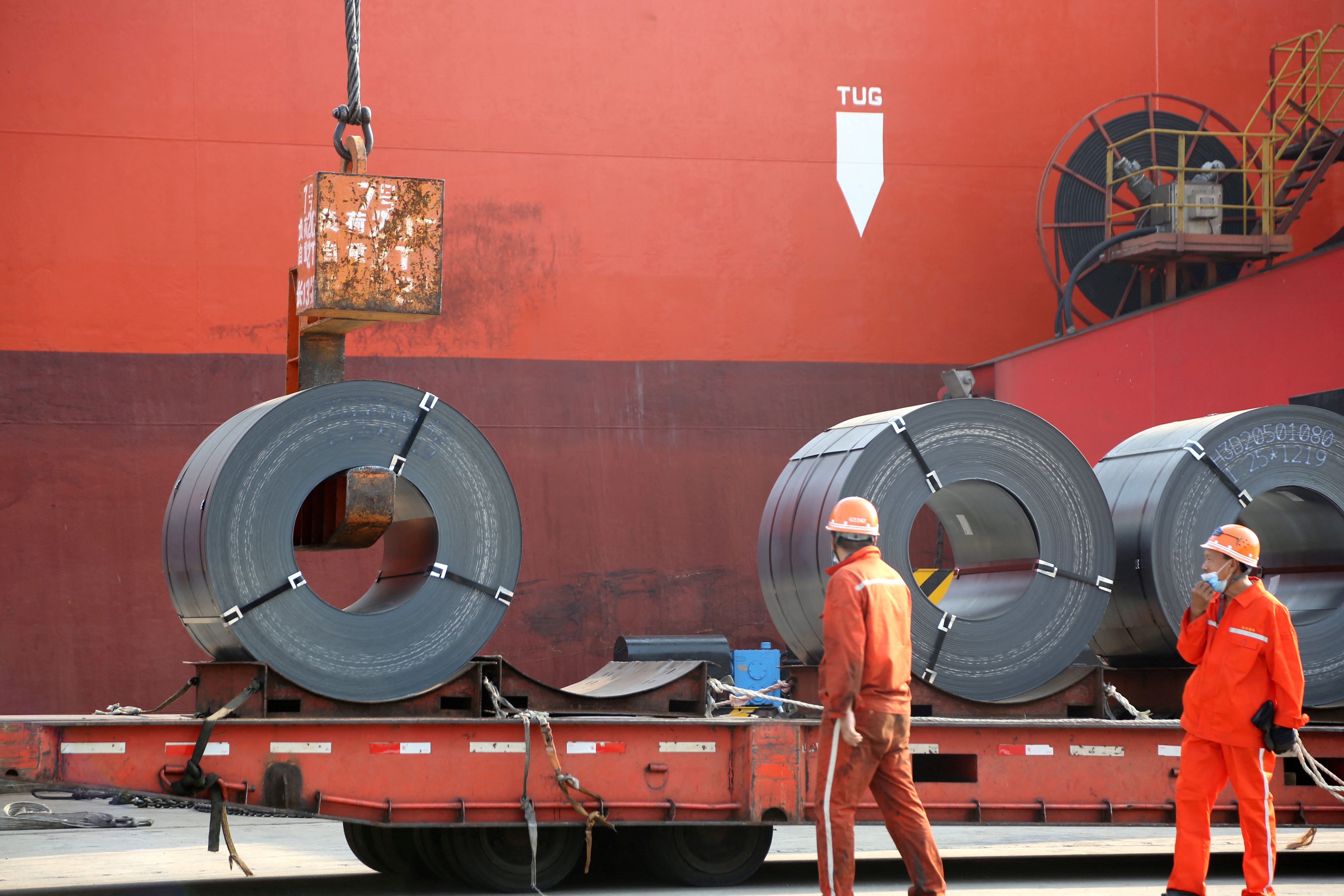 Workers load steel products for export to a cargo ship.