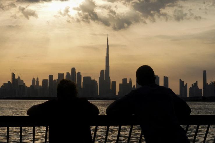 People way the sunset over Dubai, with a general view of the Dubai skyline, including Burj Khalifa