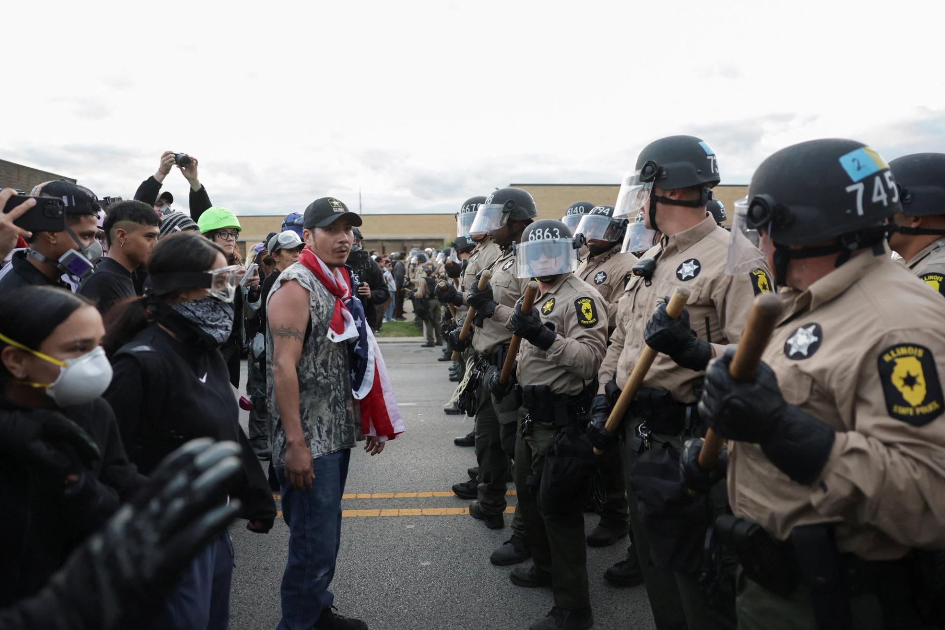 Law enforcement officers stand guard as people take part in a protest near the U.S. Immigration and Customs Enforcement (ICE) Broadview facility 