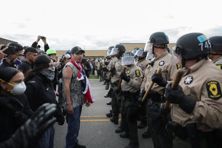 Law enforcement officers stand guard as people take part in a protest near the U.S. Immigration and Customs Enforcement (ICE) Broadview facility