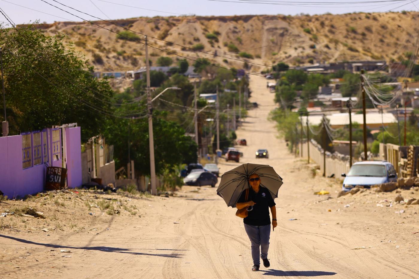 A woman walks with an umbrella during high temperatures in the Anapra neighbourhood in Ciudad Juarez, Mexico June 15, 2023. REUTERS/Jose Luis Gonzalez