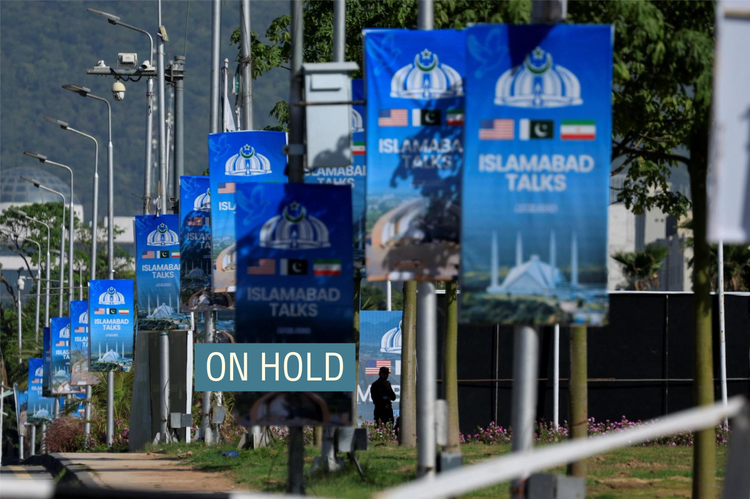 A silhouetted man stands next to advertisement posters reading “Islamabad Talks” at the Convention Centre, as Pakistan prepares to host the U.S. and Iran for the second phase of peace talks in Islamabad.