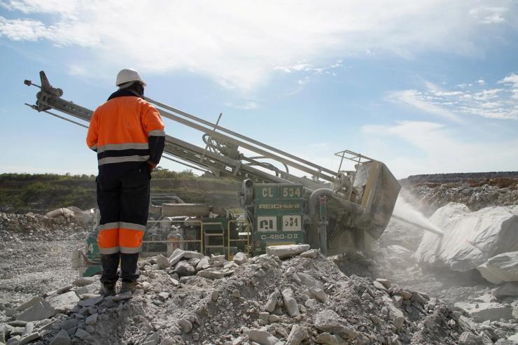 A miner observes a blast hole drill drilling into a boulder at the Kibali gold mine in Haut-Uele province, Democratic Republic of Congo.