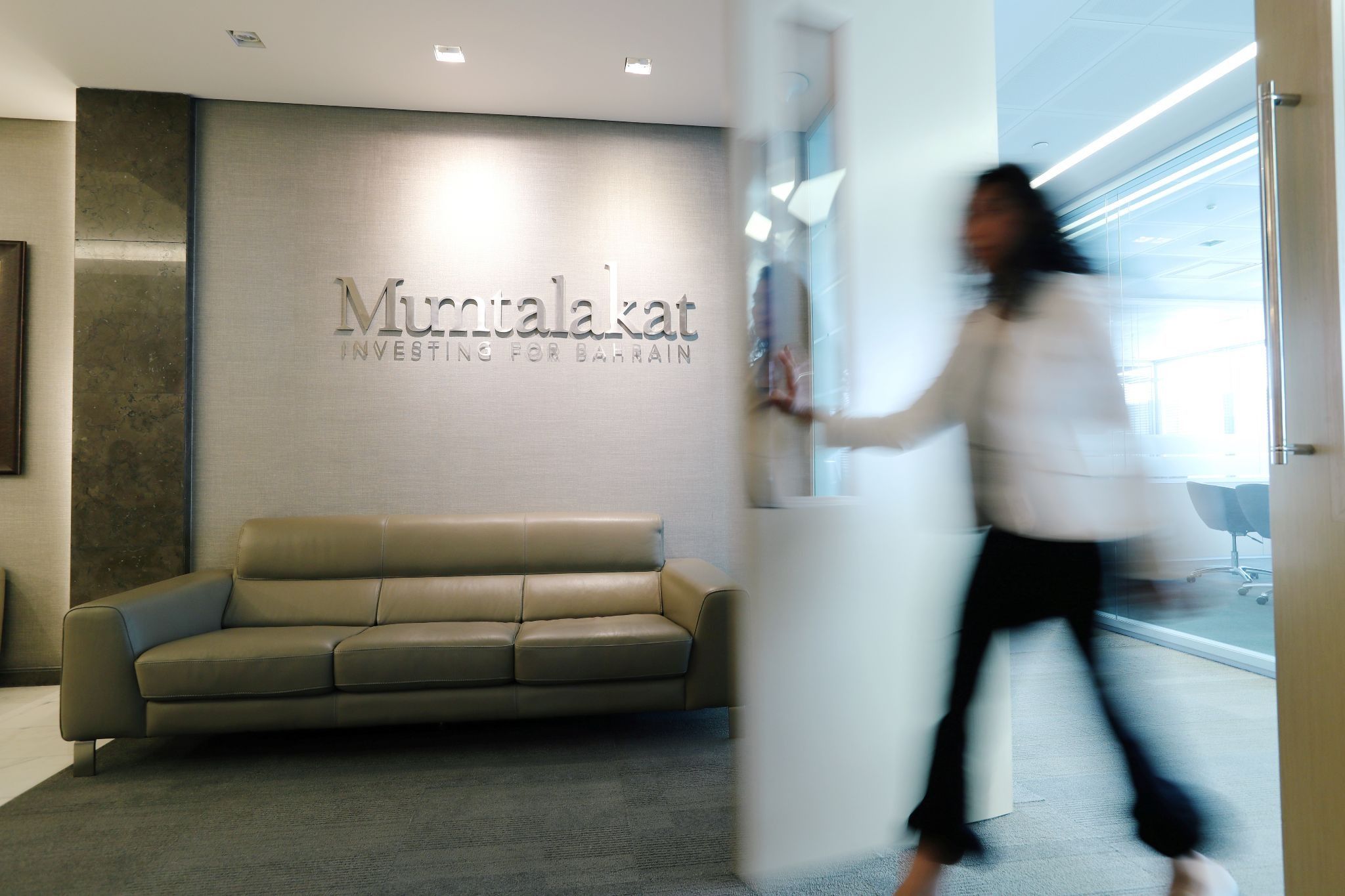 A woman walks through the door at the Mumtalakat headquarters Manama, Bahrain February 21, 2018.