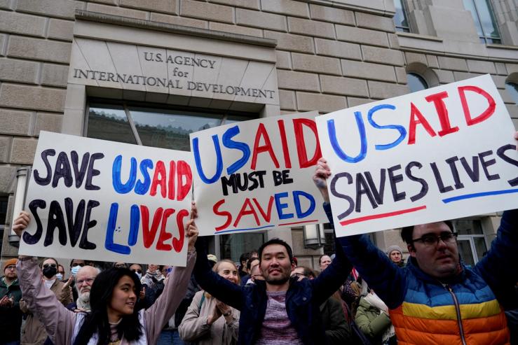 People hold placards, as the USAID building sits closed.