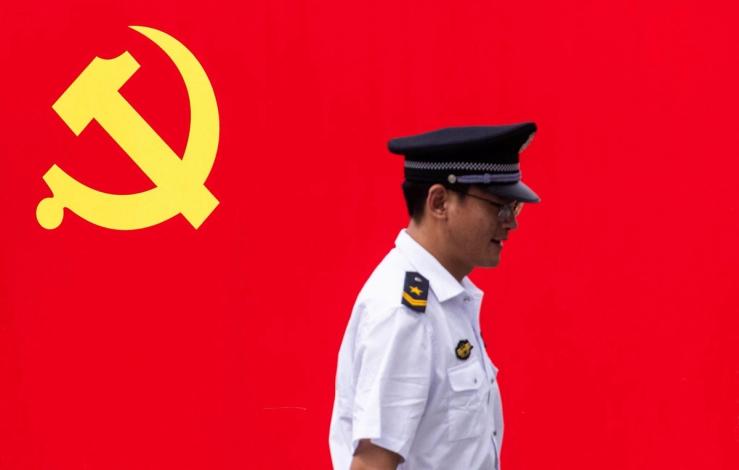 A Chinese police officer in front of a Communist flag