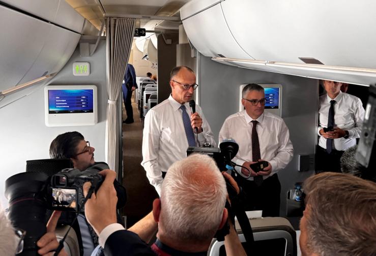 German Chancellor Friedrich Merz talks to journalists on a plane.