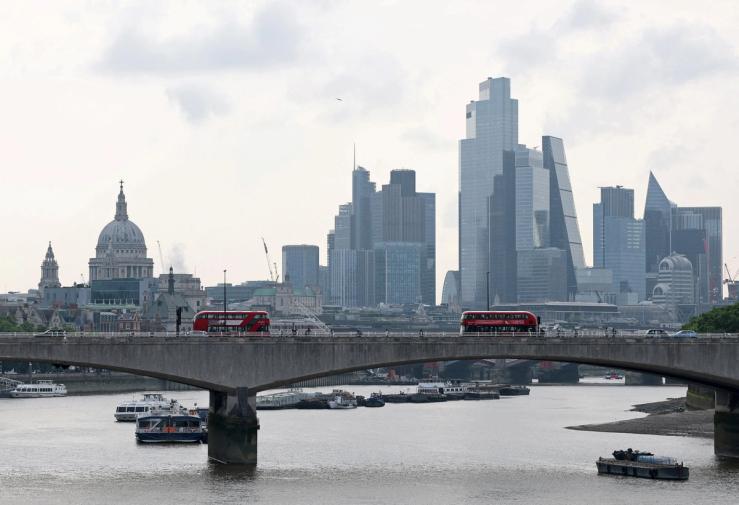 London buses cross Waterloo Bridge with St. Paul’s Cathedral and skyscrapers of the City of London business district seen behind.