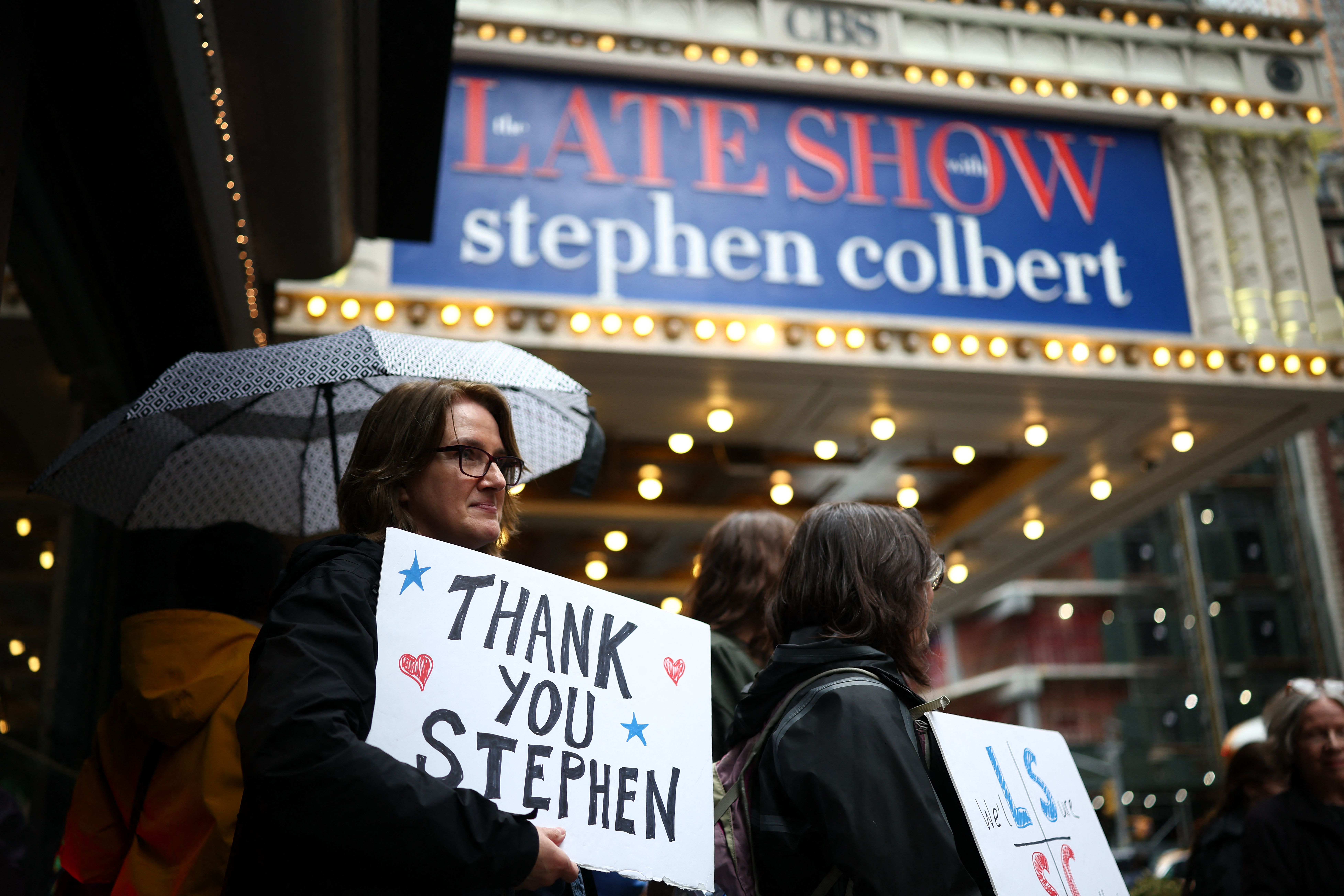 People hold signs supporting Stephen Colbert 
