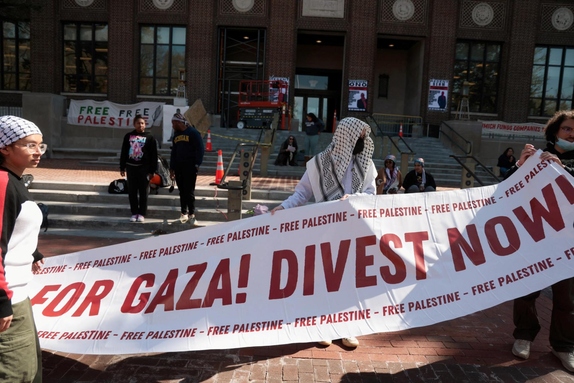 Protesters hold a banner as a coalition of University of Michigan students camp to pressure the university to divest its endowment from companies that support Israel on April 23, 2024.