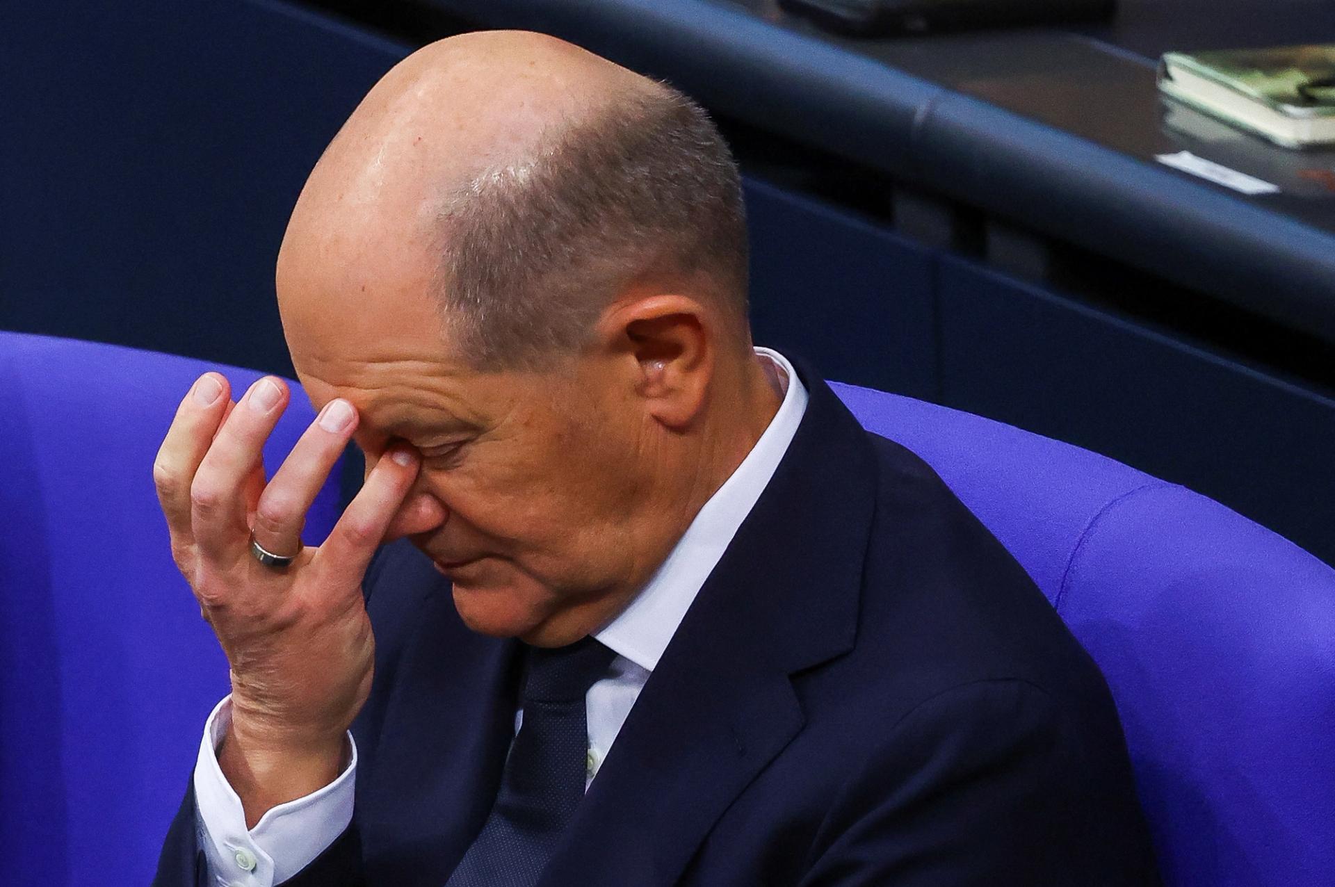 German Chancellor Olaf Scholz bows his head.