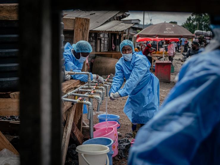 Health workers carry out hand sanitizing, handwashing and temperature screening procedures for travelers at the Kanyaruchinya checkpoint near Goma.