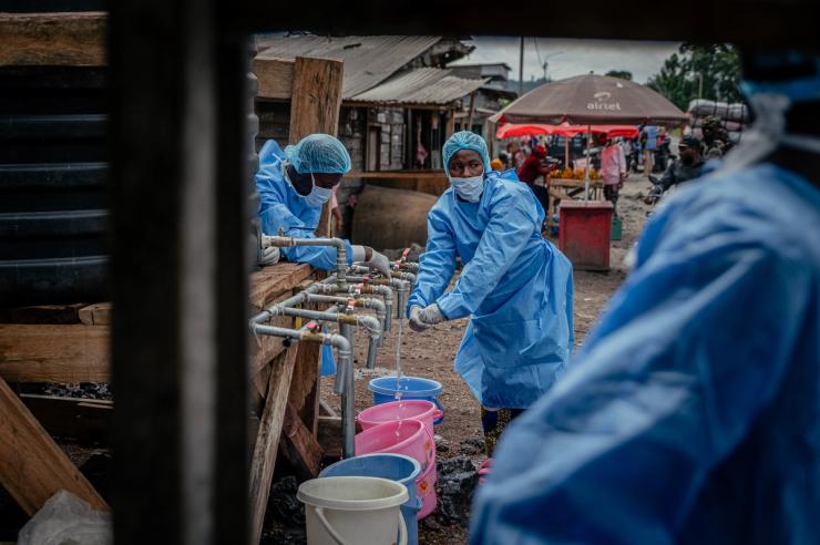 Health workers carry out hand sanitizing, handwashing and temperature screening procedures for travelers at the Kanyaruchinya checkpoint near Goma.