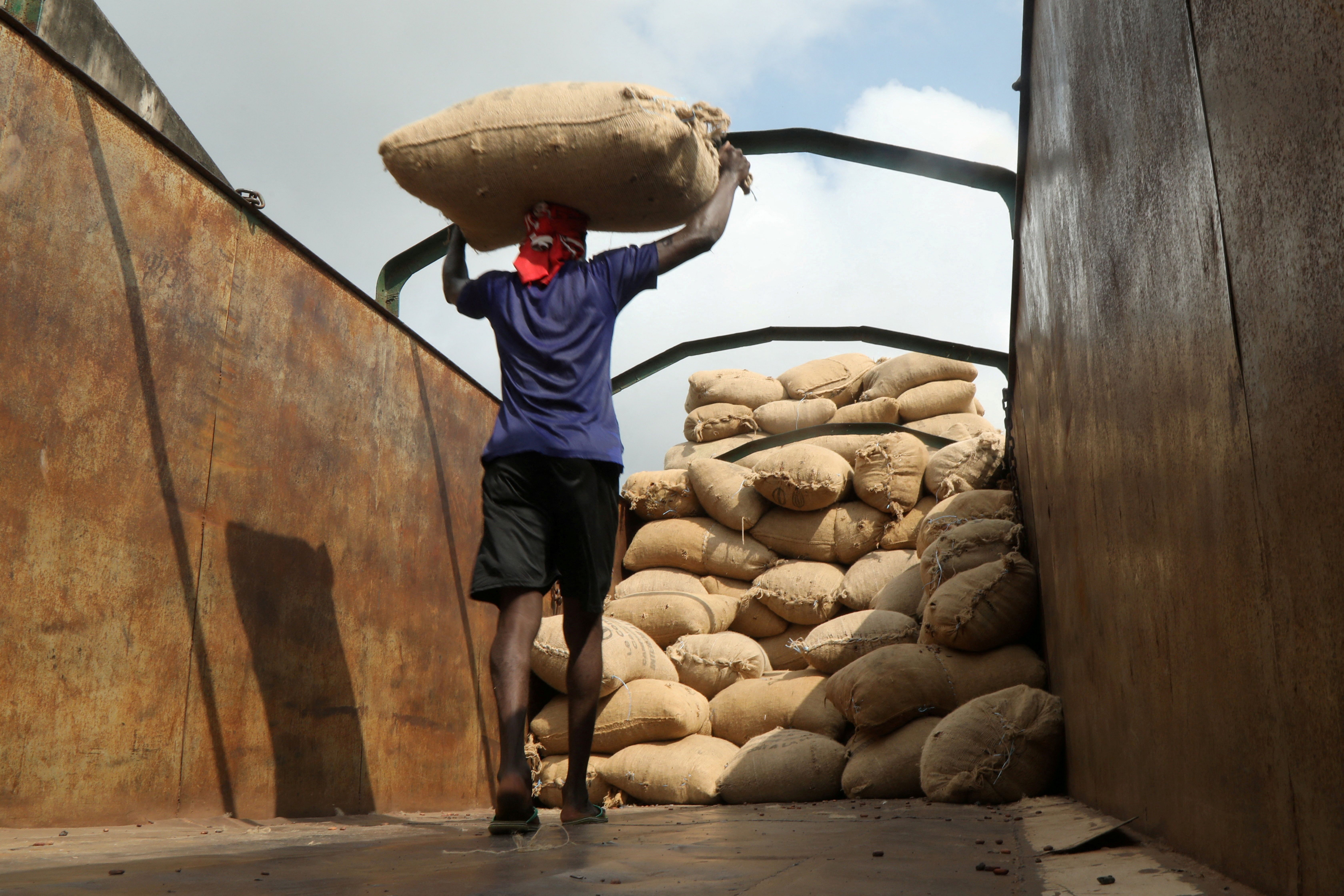 A worker carries a sack of cocoa to load it into a truck in Soubre, Côte d’Ivoire.