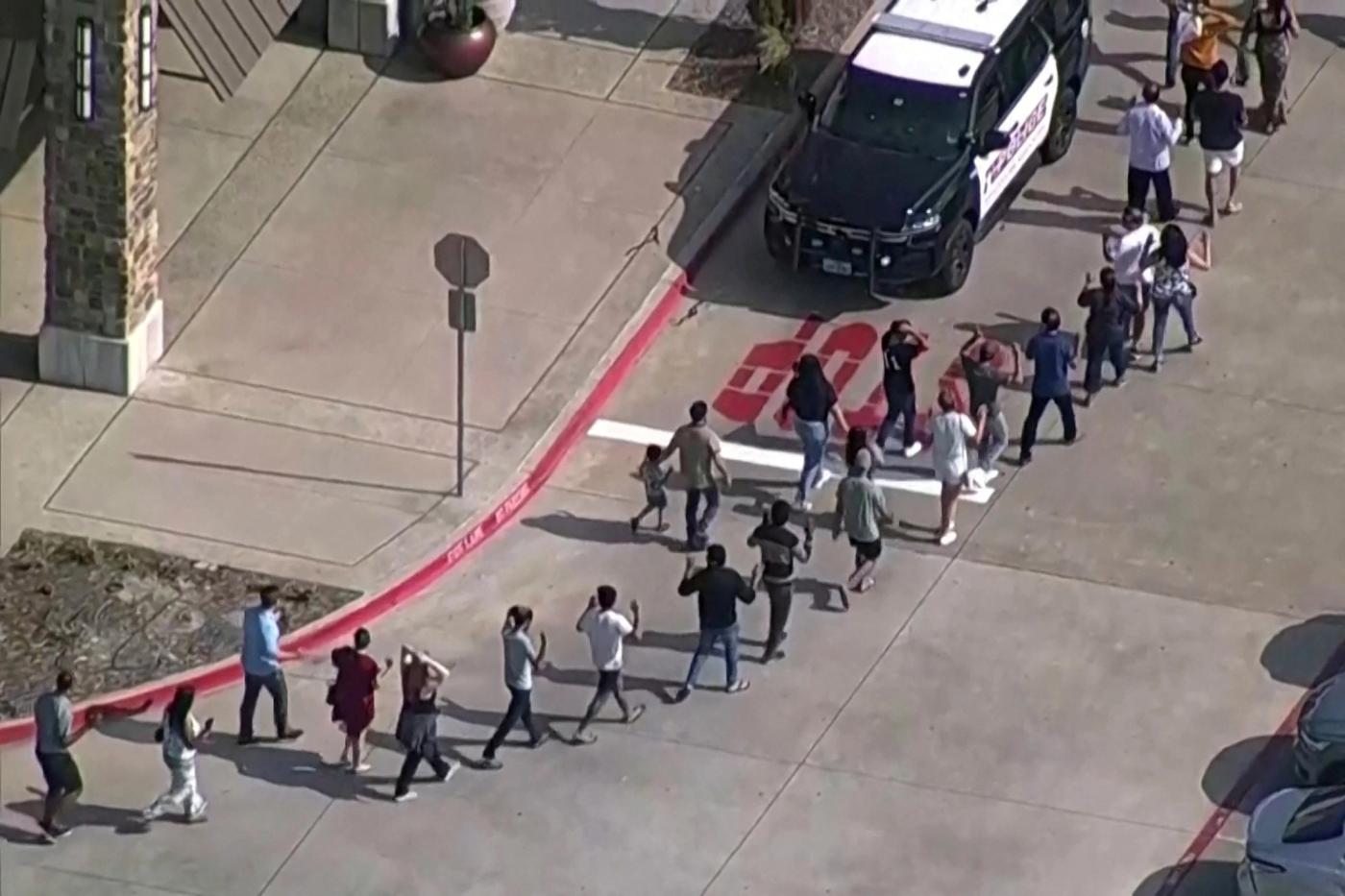Shoppers leave with hands up as law enforcement responds to a shooting in the Dallas area's Allen Premium Outlets, which authorities said has left multiple people injured in Allen, Texas