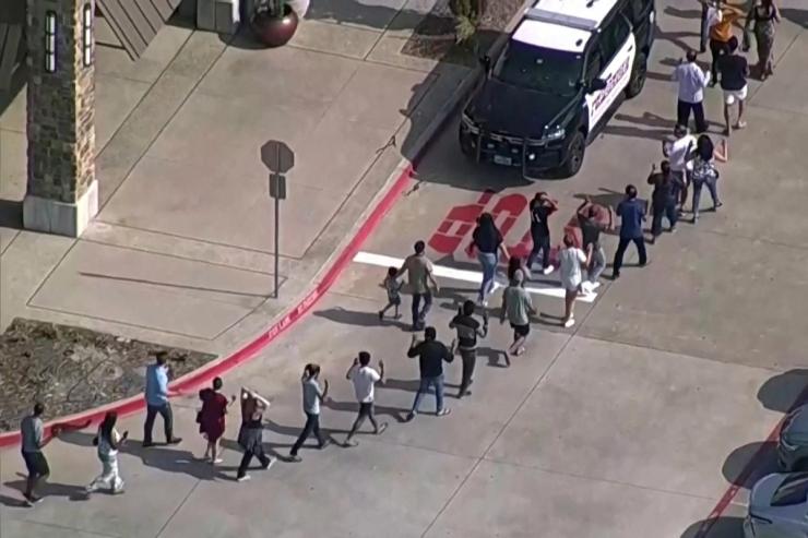 Shoppers leave with hands up as law enforcement responds to a shooting in the Dallas area’s Allen Premium Outlets, which authorities said has left multiple people injured in Allen, Texas
